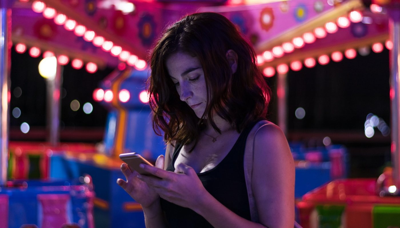 Young woman is looking her smartphone in a fair